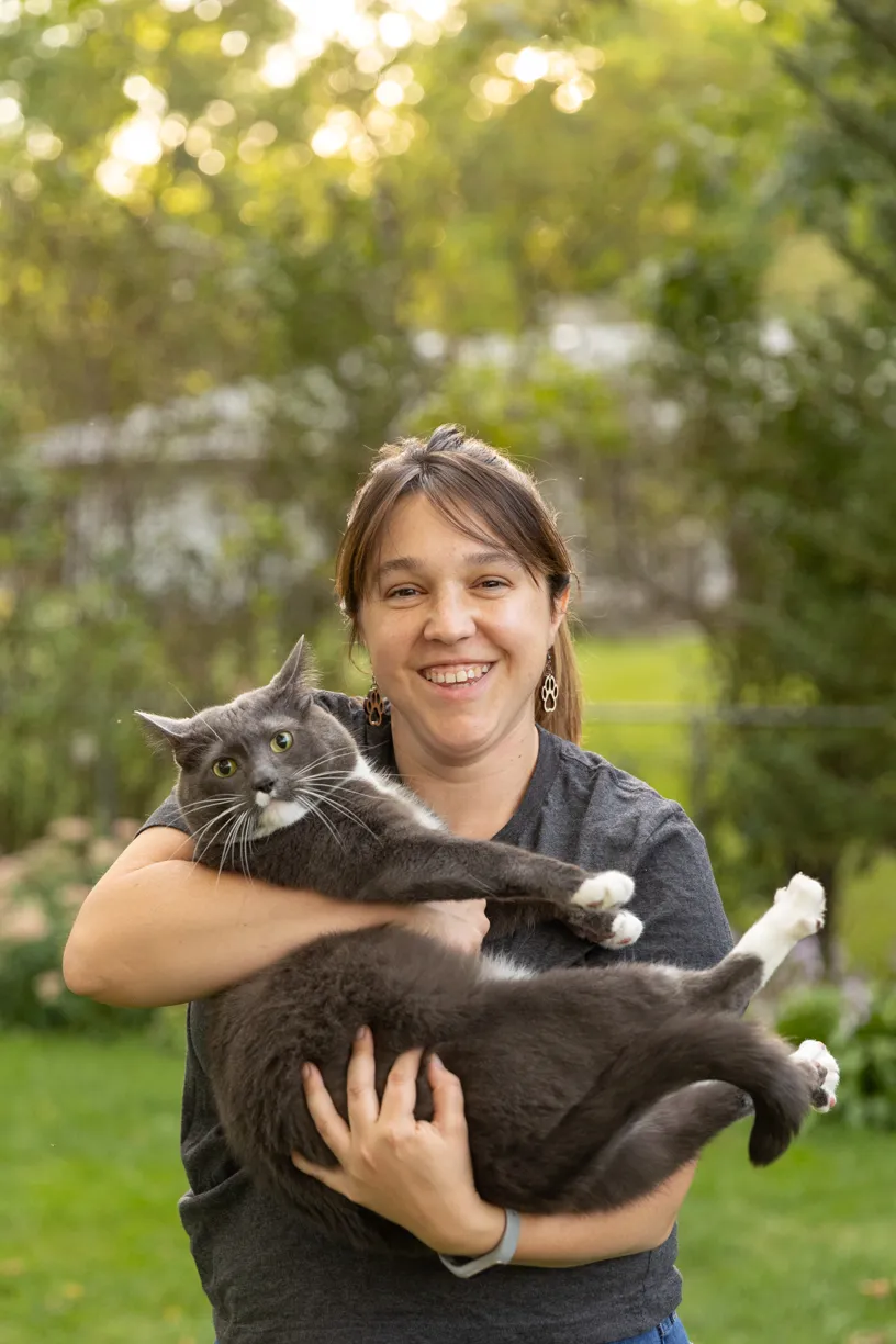 Kelly holding her grey and white cat in the garden