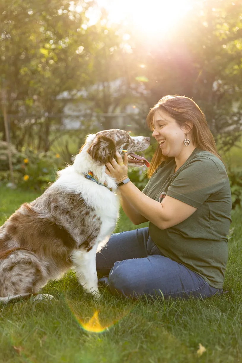 Kelly and her red merle Australian shepherd nose to nose in the backyard