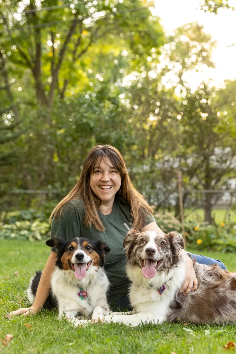 Kelly lying in the grass with her two dogs