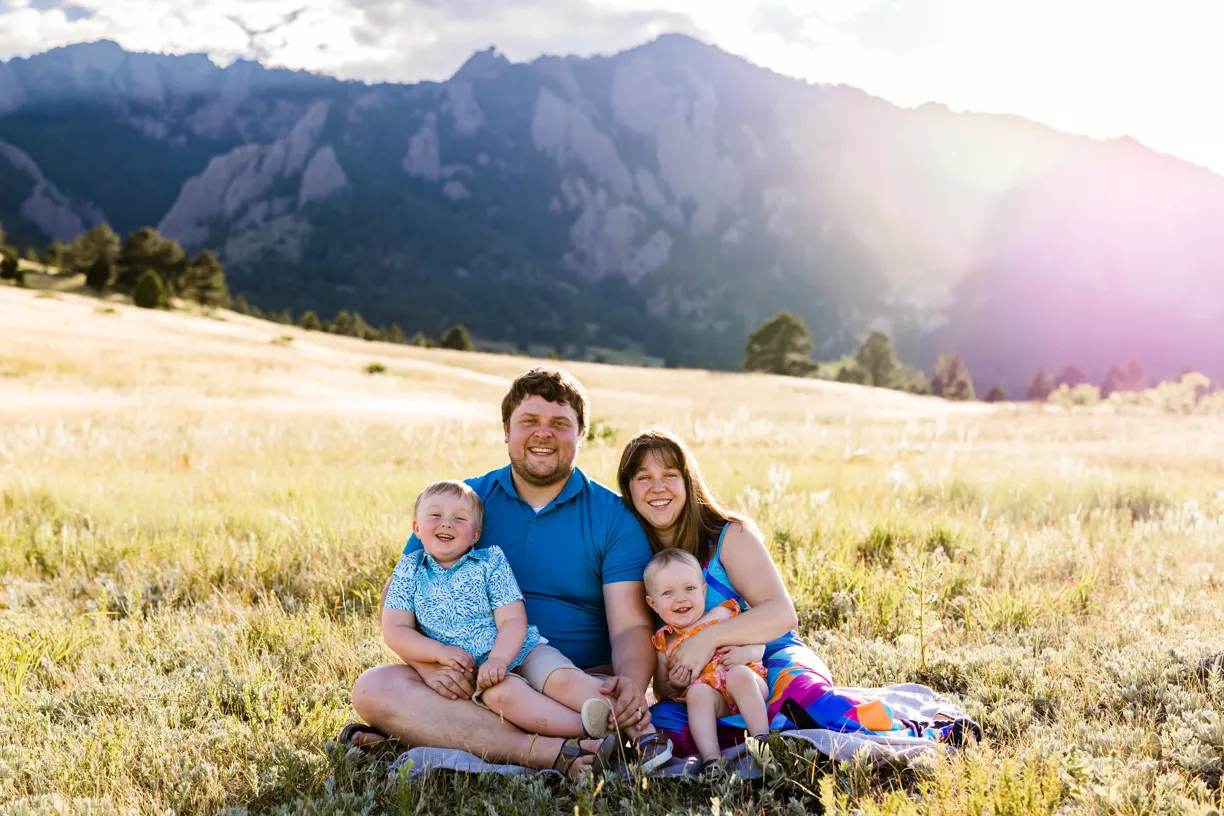 Kelly’s family sitting in a mountain meadow with their two young children